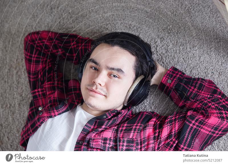 Porträt eines jungen Mannes mit Kopfhörern, der fröhlich lächelt. Typ Lügen Teppich sich[Akk] entspannen Musik heimwärts Lifestyle lässig Menschen Kaukasier