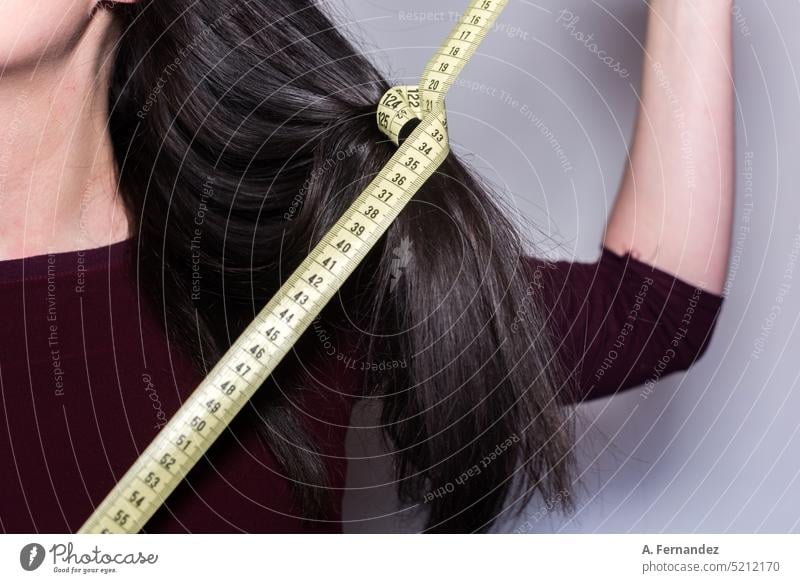 Frau hält ein gelbes Maßband um eine Strähne ihres langen Haares. Haare & Frisuren feminin Behaarung Messinstrument messen Messung Messvorrichtung Klebeband