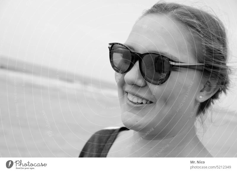 junge Frau , lächelnd am Strand natürlich Zufriedenheit Lebensfreude Potrait Gesicht feminin Fröhlichkeit Freude Strahlen lachen Sonnenbrille Porträt positiv