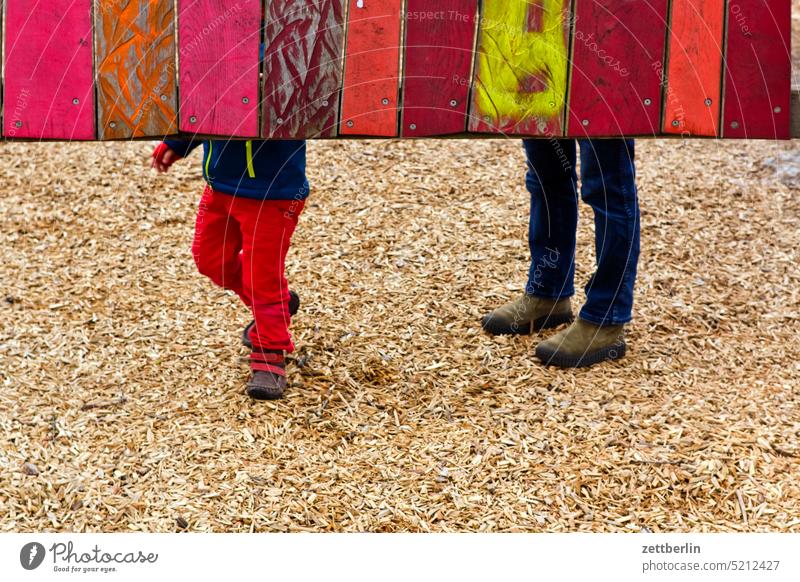 Enkel und Oma auf dem Spielplatz spielplatz sandplatz kind erwachsener mensch kind oma enkel fuß bein hose wand holz holzwand spielen verstecken versteckt leben