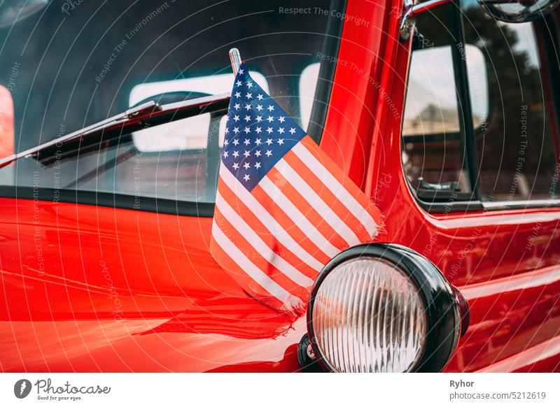 Red Pickup Truck With Small American Flag Waving. Close Side View Of Red Pickup Truck American Flag Waving. 4. Juli Urlaub. Amerikanische Flagge weht im Wind. Unabhängigkeitstag
