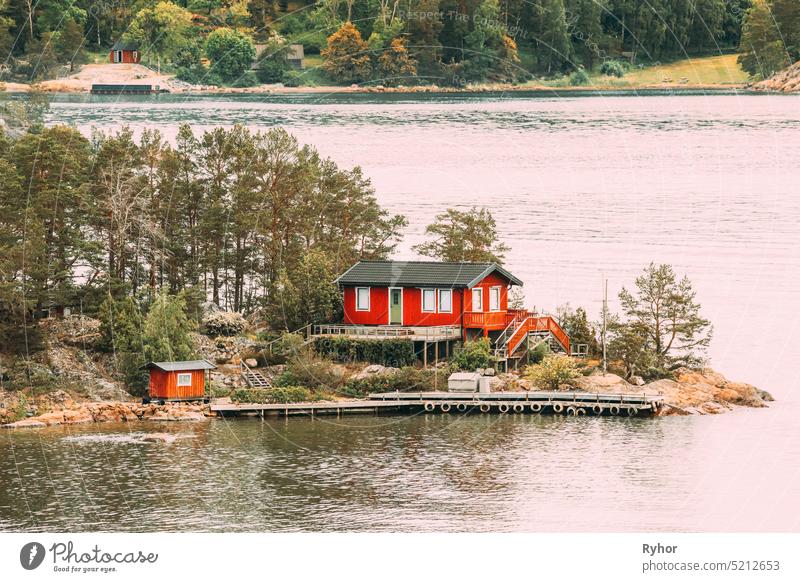 Schweden. Viele schöne rote schwedische Holzblockhaus Haus auf Rocky Island Küste im Sommer. See oder Fluss Landschaft Hütten Hygge reisen Natur traditionell