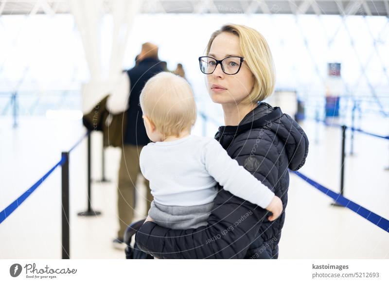 Mutter carying seinen Säugling Junge Kind Warteschlange am Flughafen-Terminal in Passkontrolle Linie bei der Einwanderung Abfahrt vor dem Umzug in das Boarding Gates ein Flugzeug zu besteigen. Reisen mit Baby-Konzept.