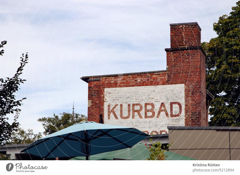 kurbad steht an der ziegelwand schrift aufgemalt mauer fassade gebäude schornstein draußen sonnenschirm terrasse café kulturdenkmal museum kassel