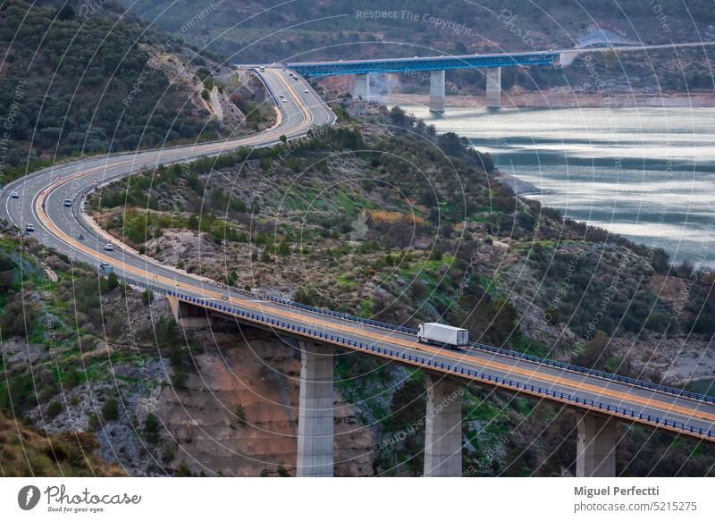 Kühltransporter auf einer Autobahn mit Brücken über einen Sumpf, Straßenlandschaft in den Bergen und neben einem Damm. Lastwagen Kühlschrank Viadukt Landschaft