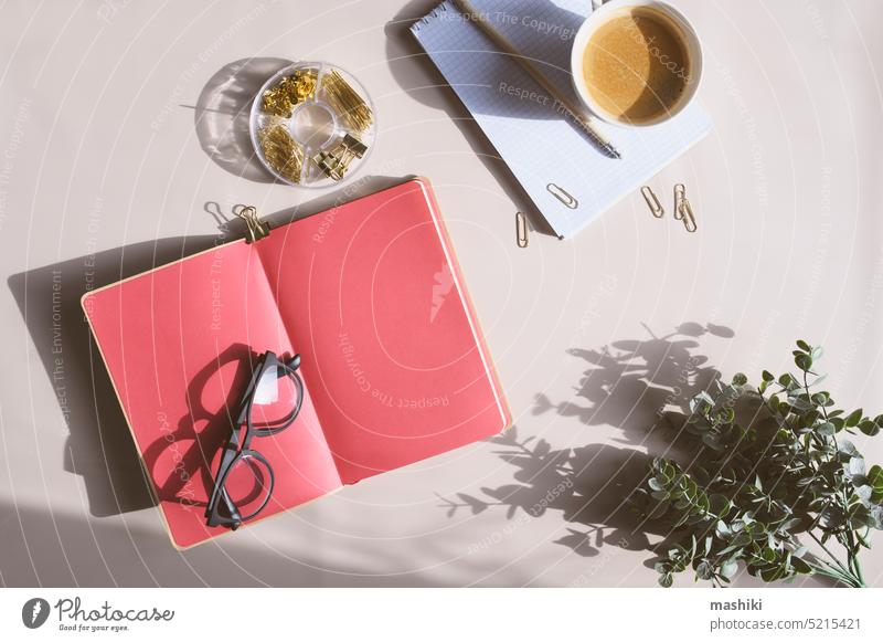 Ästhetischer minimalistischer Arbeitsbereich in trendigen Farben 2023. Home-Office, Blog und Social-Media-Konzept. Flat legen von Notizbuch, Kaffee und Gläser in der Morgensonne
