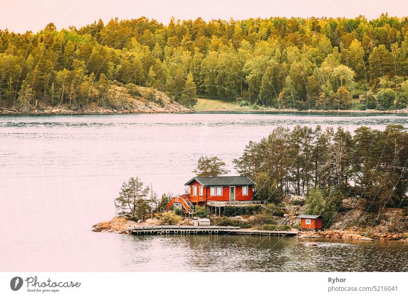 Schweden. Viele schöne rote schwedische Holzblockhaus Haus auf Rocky Island Küste im Sommer. See oder Fluss Landschaft Hütten Hygge reisen Natur traditionell