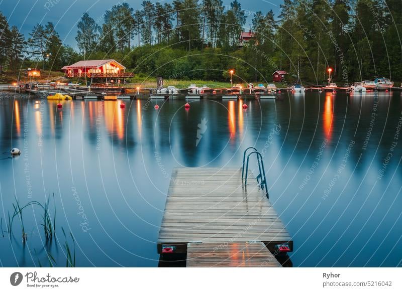Schweden. Schöne hölzerne Pier in der Nähe von See im Sommer Abend Nacht. See oder Fluss Landschaft Reflexion & Spiegelung Windstille Schönheit in der Natur