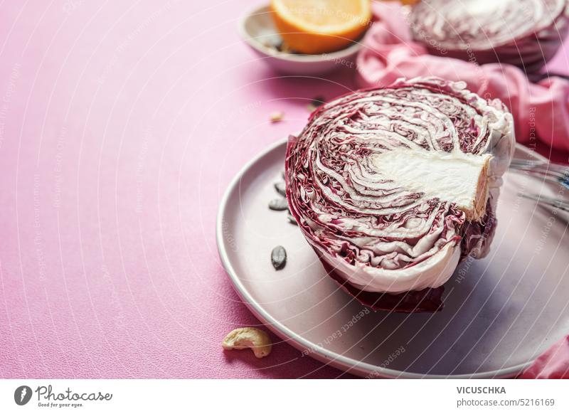 Halbierter Radicchio auf einem Teller vor rosa Tischhintergrund, Rand halbiert Hintergrund Borte Salatbeilage Essen zubereiten Bestandteil roh Gesundheit Gemüse