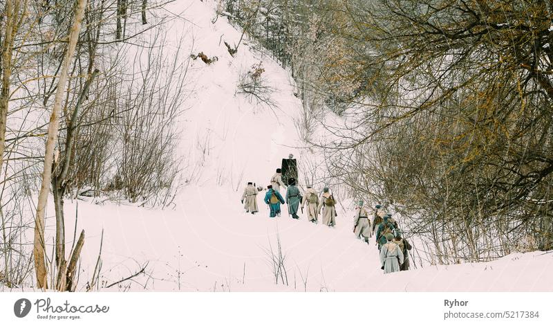 Männer, gekleidet als Soldaten der Weißen Garde der kaiserlich-russischen Armee zu Zeiten des russischen Bürgerkriegs, marschieren durch einen verschneiten Winterwald. Historisches Reenactment 1917-1922.