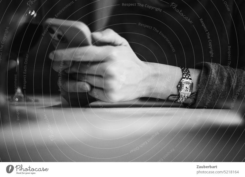 Gefaltete Hände mit Handy, Armbanduhr, Tischplatte gefaltet Uhr lesen checken Aufmerksamkeit Ablenkung Lifestyle Telefon Mobiltelefon Smartphone benutzend