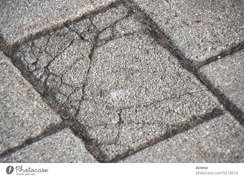 Sprung in der Platte Stein Riss kaputt alt Sprünge Verfall Boden bersten verwittert Beton Pflastersteine Straßenbelag Fugen diagonal Haarriss zerbrochen grau