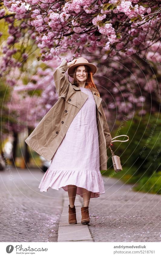 Schöne junge brünette Frau mit langen, im Wind wehenden Haaren und braunem Hut in einem blühenden Garten. geringe Tiefenschärfe. Frühlingstag Park schön Mädchen