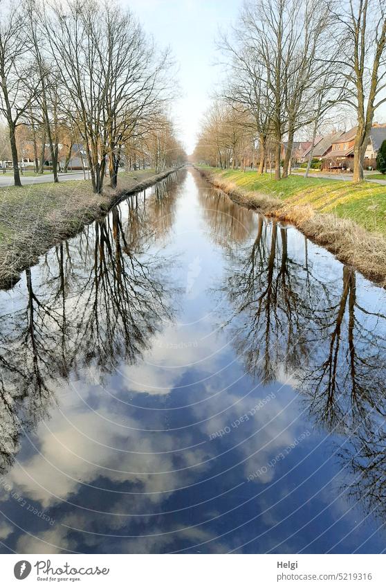 Bäume spiegeln sich bei schönem Wetter an beiden Seiten eines kleinen Kanals Wasser Spiegelung Baum Allee Frühjahr schönes Wetter Himmel Wolken Natur Landschaft