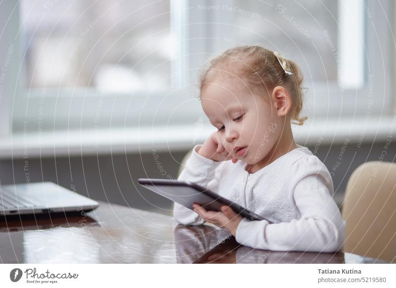 Kind mit einem Tablet am Tisch. Platz zum Kopieren Technik & Technologie Tablette digital Internet Bildung niedlich Kindheit Gerät wenig heimwärts heiter