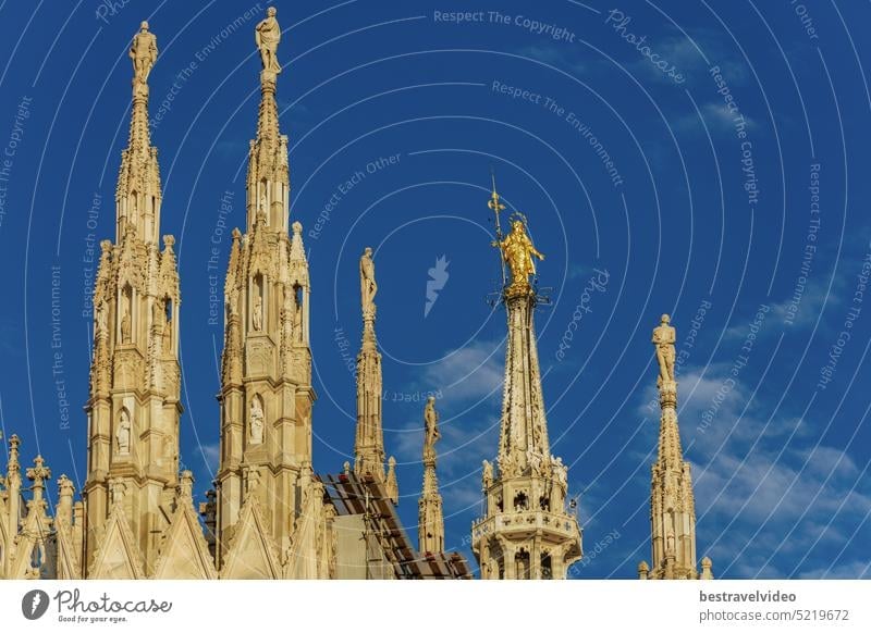 Mailand, Italien Tagesansicht der Dächer der römisch-katholischen Kathedrale im gotischen Stil auf dem gleichnamigen Hauptplatz mit der Madonnenstatue, der Kleinen Madonna und dem goldenen Kunstwerk der Jungfrau Maria vor dem blauen Himmel.