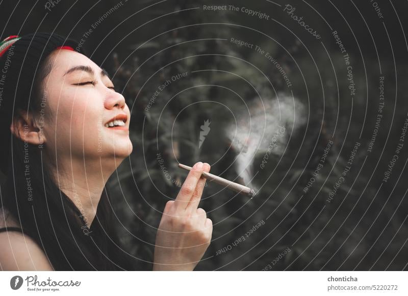 Yong Asia Frau raucht Marihuana an Cannabis Baum Pflanze Hintergrund Süchtige Erwachsener attraktiv schön Schönheit schwarz Kaukasier heiter Zigarette