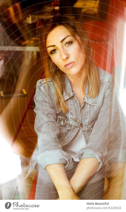 Frau sitzt im Restaurant, durch das Fenster fotografiert Model ausblick Jeansjacke Jeanshose Jeansstoff rot Creolen Schmuck Diner USA America weiblich Makeup