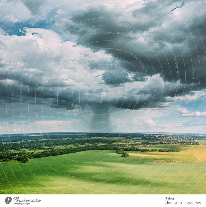 Aerial View Of Rain Above Countryside Rural Field Or Meadow Landscape With Green Grass Under Scenic Spring Dramatic Sky With White Fluffy Clouds. Regenwolken am sonnigen Tag. Ansicht aus der Vogelperspektive