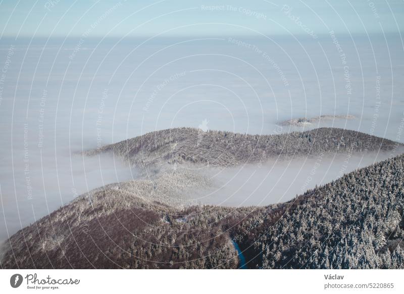 Die Berghänge der Beskiden in der Tschechischen Republik versinken in einer dicken weißen Inversion, die von den Städten aufsteigt. Winterlandschaft Umkehrung