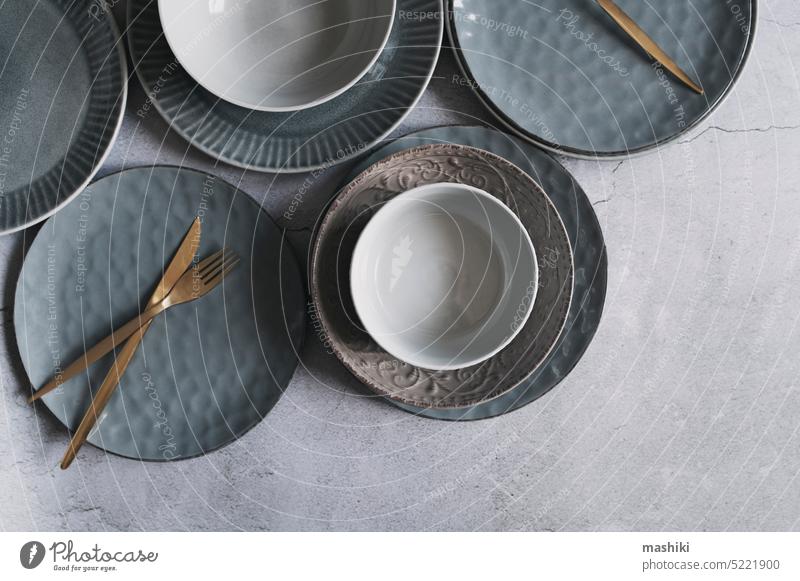 Set aus grauen modernen Keramiktellern mit goldenem Besteck. Geschirr trendy Kollektion. Speise Teller leer Sauberkeit Hintergrund Lebensmittel Küche Abendessen