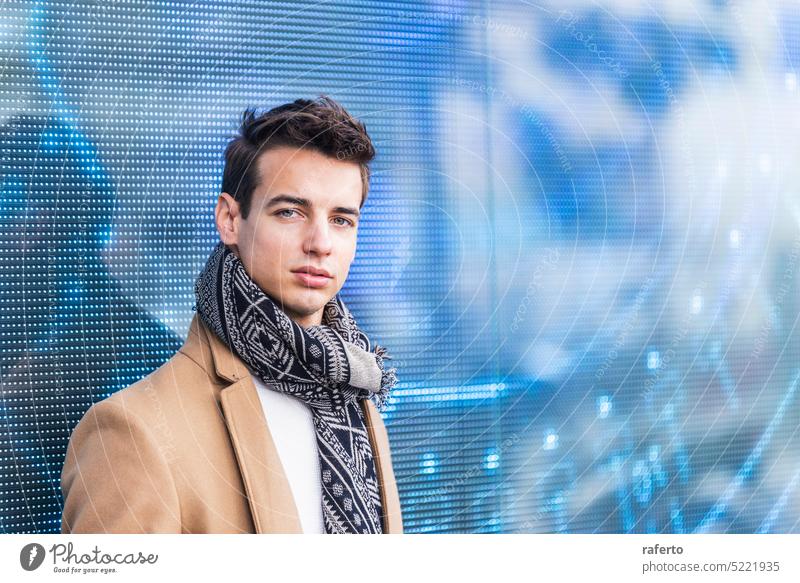 Porträt eines stilvollen, gut aussehenden jungen Mannes mit Mantel, der im Freien steht und sich an eine geführte Tafel lehnt Erwachsener Fotokamera Kaukasier