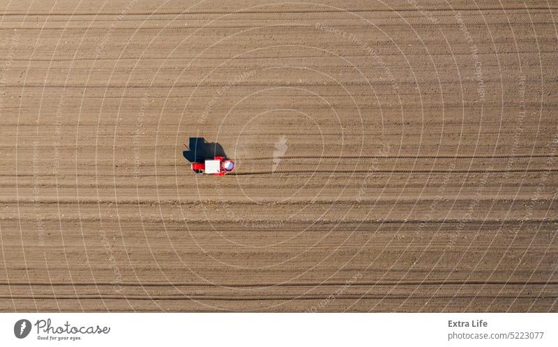 Luftaufnahme eines Traktors beim Ausbringen von Dünger auf einem landwirtschaftlichen Feld oben Ackerbau anbaufähig künstlich Gerste Pflege Müsli Chemikalie