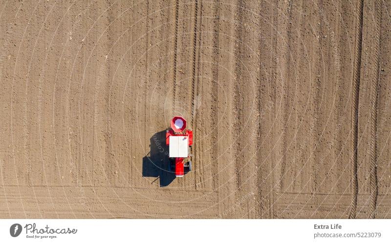 Luftaufnahme eines Traktors beim Ausbringen von Dünger auf einem landwirtschaftlichen Feld oben Ackerbau anbaufähig künstlich Gerste Pflege Müsli Chemikalie