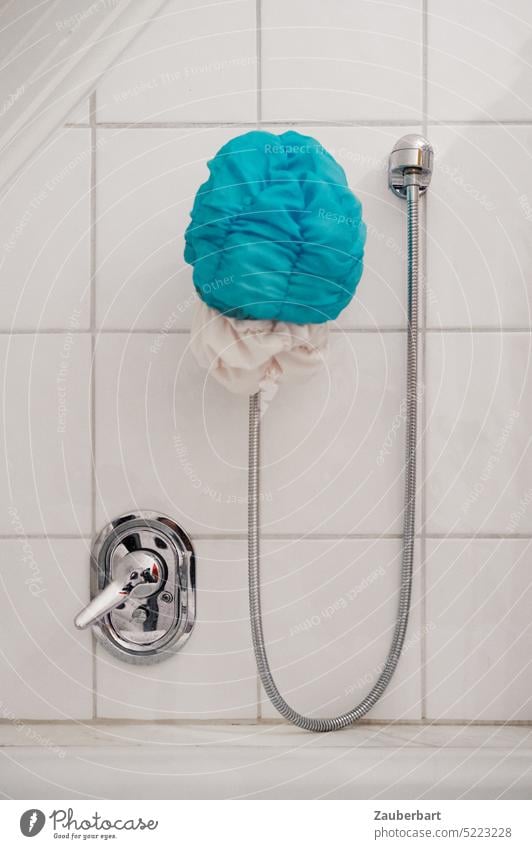 Blaue Duschhaube, Schlauch im Bogen und Armatur in Chrom vor weißen Fliesen blau dusche duschen Mischbatterie chrom hängen Badezimmer reinigung Fugen