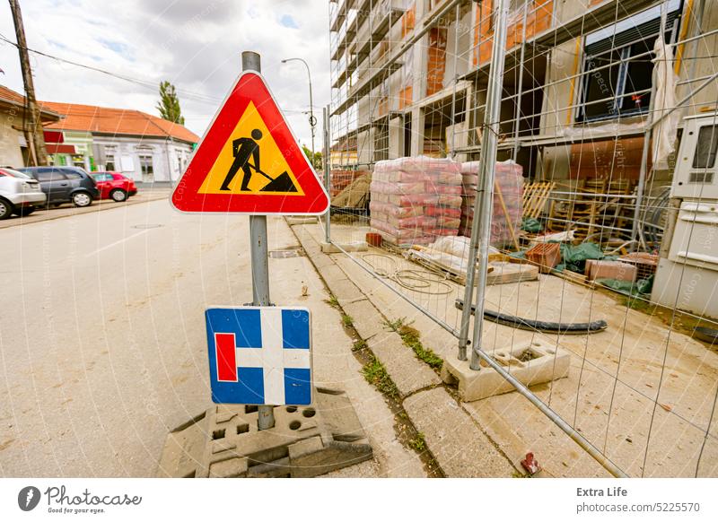 Verkehrsschilder auf der Straße neben dem eingezäunten, noch nicht fertig gestellten Bauwerk. Betreten der Baustelle verboten, Arbeiten im Gange nähern Gegend