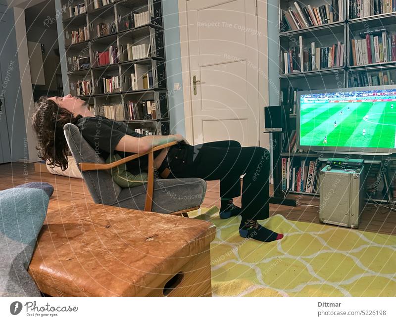 Erschöpfter junger Mann auf Sessel verpasst das Fußballspiel Junger Mann schlafen Wohnzimmer TV verpassen