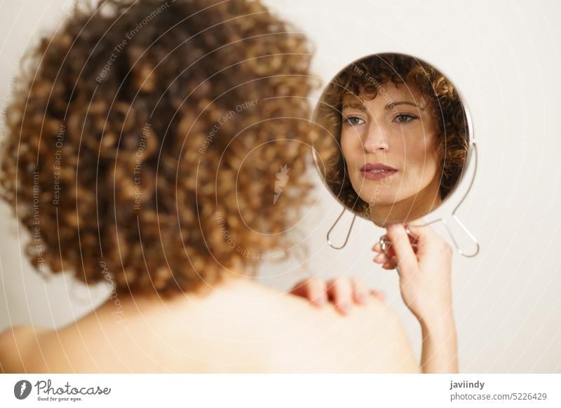 Charmante erwachsene Frau mit Make-up suchen Reflexion im Spiegel Reflexion & Spiegelung krause Haare Vorschein Model selbstbewusst Schönheit Stil feminin jung