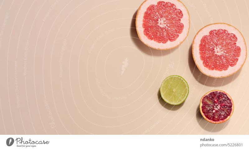 Geschnittene Orangen-, Limetten- und Grapefruitstücke auf beigem Hintergrund, Ansicht von oben orange Zitrone frisch Zitrusfrüchte Lebensmittel keine Menschen