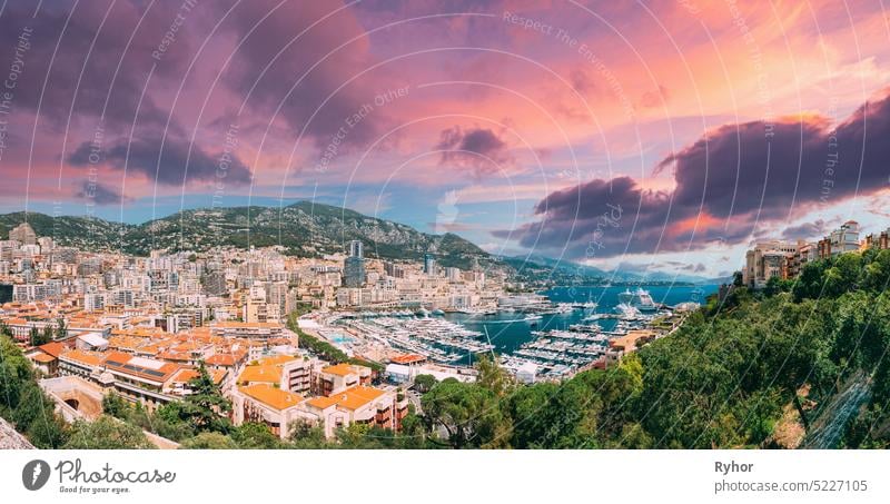 Monaco, Monte Carlo Stadtbild. Immobilien Architektur auf Berg Hügel Hintergrund. Viele Hochhäuser in der Innenstadt. Yachten am Kai der Stadt in Sunny Summer Day vertäut. Geänderte Sonnenuntergang Himmel
