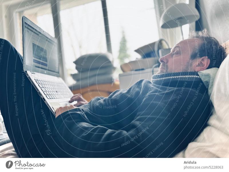 Mann liegt krank im Bett und macht Homeoffice Computer Laptop online Arbeitsplatz Internet arbeiten Büro digital Business Arbeit & Erwerbstätigkeit Job Tastatur