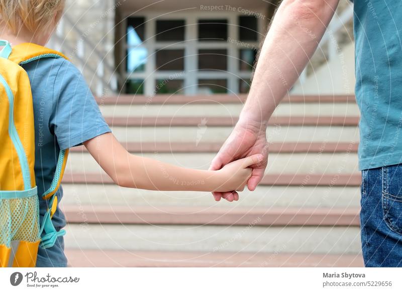Kleiner Schuljunge geht mit seinem Vater nach den Sommerferien zur Schule. Ein Elternteil begleitet das Kind oder trifft es. Hochwertige Bildung für Kinder.