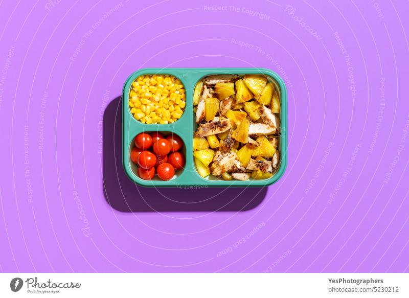 Sommersalat in einer Lunchbox, Ansicht von oben auf lila Hintergrund. Tropisches Gericht in einem Silikonbehälter. Kasten hell Kirsche Hähnchen Farbe Container
