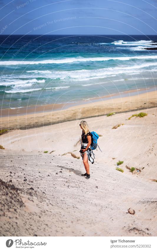Wanderin mit Rucksack, die eine Sanddüne in Richtung des einsamen Strandes hinuntergeht. Sao Vicente Kap Verde sao vicente verde Frauen Strand nach unten