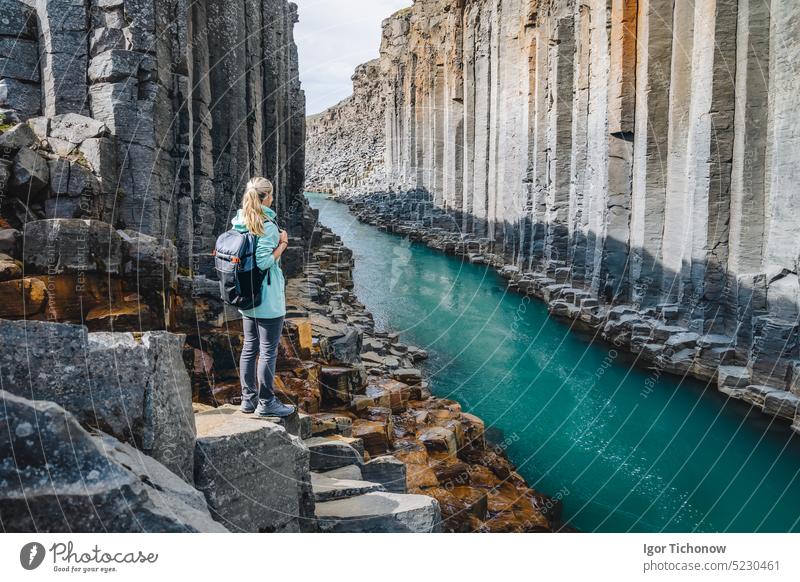 Wanderin mit Rucksack in der Studlagil-Schlucht. Einzigartige Jokulsa Basaltsäulen und A Bru Fluss. Spektakuläre Outdoor-Szene von Island, Europa. Schönheit der Natur Konzept Hintergrund