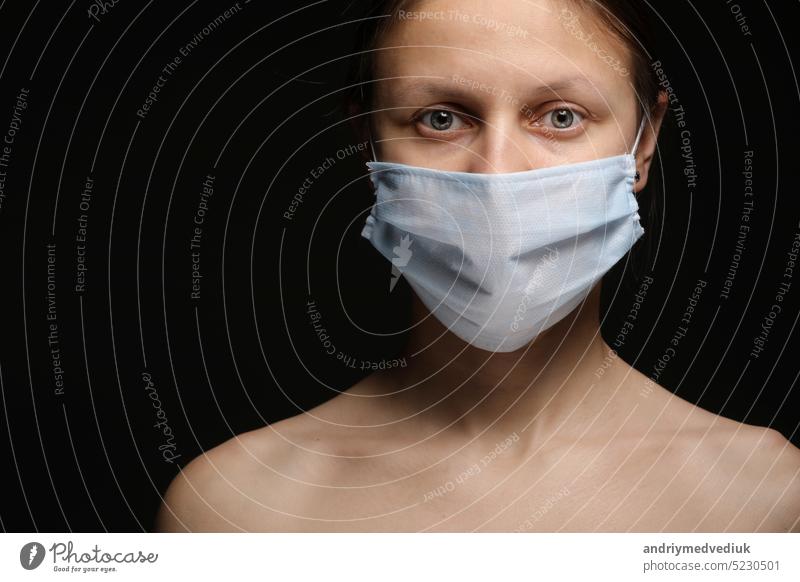 Junge Frau trägt eine Schutzmaske während des Ausbruchs der Coronavirus-Krankheit COVID-19. Nahaufnahme Studio-Porträt auf schwarzem Hintergrund. Mundschutz