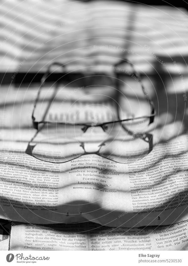 Schattenspiel Brille auf Zeitung mit Schattenwurf Licht Kontrast Licht & Schatten abstrakt Silhouette schwarz Strukturen & Formen Menschenleer