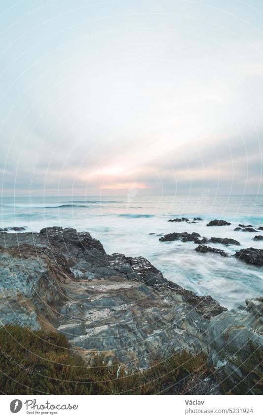 Der stürmische Atlantik zeigt seine Kraft, wenn die Wellen bei Sonnenuntergang vor Porto Covo, Portugal, gegen die Felsen schlagen. Die Schönheit des Fisherman Trail, Rota Vicentina