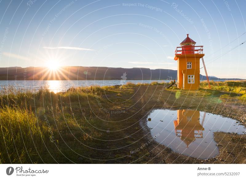 Augustsonne am Fjord auf einer Bank an einem leuchtend orangenen Leuchttürmchen genießen. Leuchtturm Leuchtfeuer leuchtende Farbe Abendsonne stürzende Linien