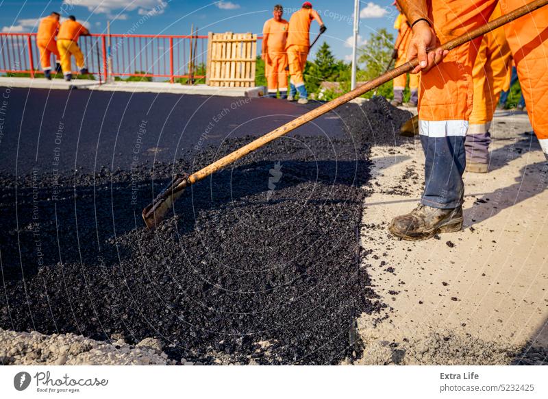 Arbeiter benutzen Schaufeln, um den heißen Asphalt auf das richtige Maß zu bringen ausrichten Ausrichten Ausrichtung Asphaltierung Bitumen Blacktop Brücke