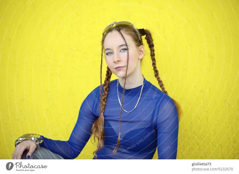 Raver Girl - gestylt mit Zöpfen in coolem, blauen Techno Outfit vor gelber Wand Porträt Mädchen Jugendliche Teenager-Mädchen Außenaufnahme junge Frau