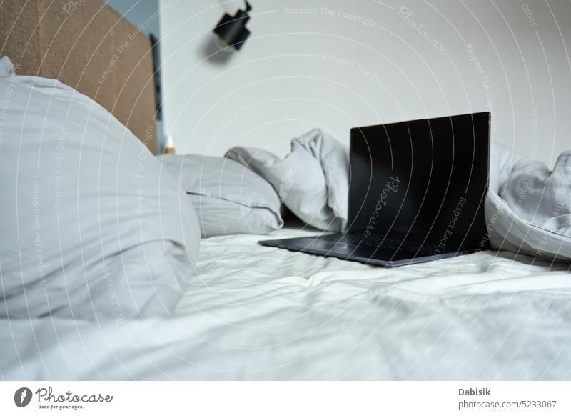 Ungemachtes Bett mit Kissen und zerknitterten Laken und offenem Laptop Hintergrund Freiberufler heimwärts Schlafzimmer Arbeitsplatz freiberuflich bequem