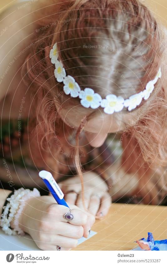 Mädchen mit Blumenkranz schreibt einen Brief Margarite Schüler Schule schreiben Abitur Abschied Papier Bildung lernen Hand Farbfoto pädagogik