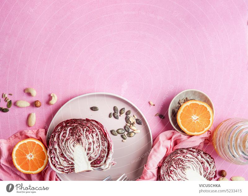 Halbierter Radicchio auf Teller mit gesunden Zutaten für veganen Salat auf rosa Hintergrund, Ansicht von oben. Umrandung halbiert Gesundheit Veganer
