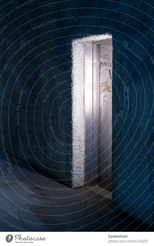 Einsame Tür eines Fahrstuhls, Stahltür, beleuchtet in düsterem Flur Licht Beton unheimlich dunkel low key Gefahr Angst gefährlich gruselig Schatten Low Key