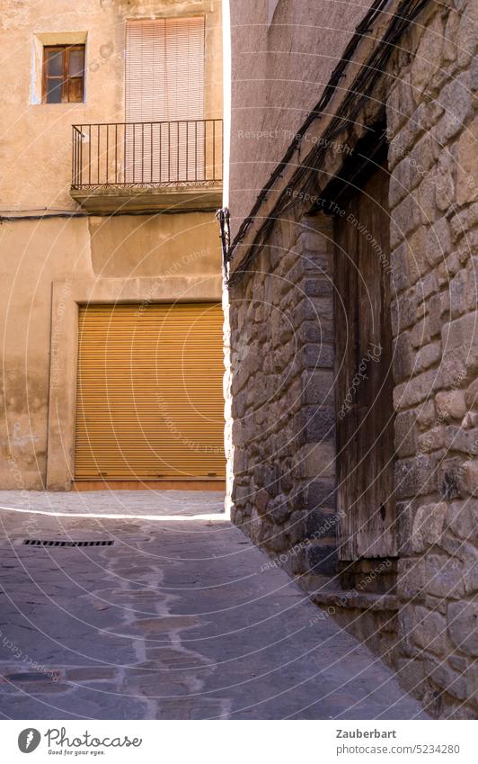 Gasse einer katalanischen Stadt, Steinmauer, Garagentor und Lichtrahmen Dorf Katalonien Mauer Rahmen braun beige Form Struktur Weg mittelalterlich beengt Ausweg